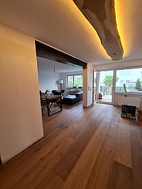 Gemütliches Wohnzimmer mit Holzfußboden und einer modernen Deckenleuchte.